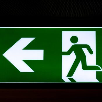 Green emergency exit sign on black background